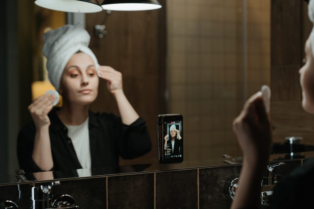 O femeie care poartă un prosop în fața unei oglinzi, arătându-și creșterea Instagram.
